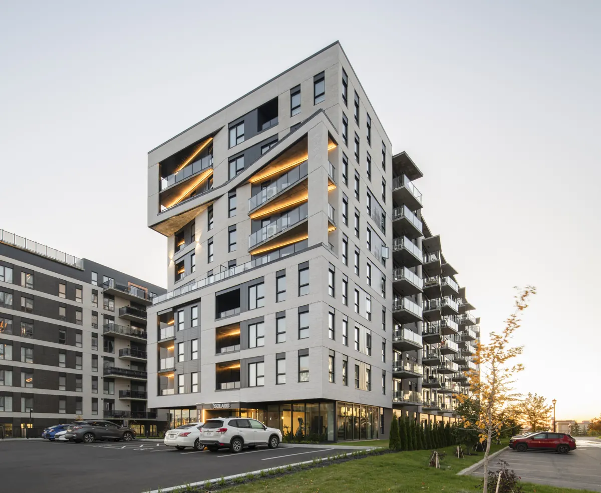 Solaris et ses balcons éclairés, vus du stationnement